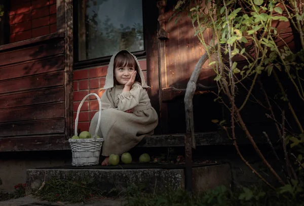 Dreaming girl with apples on a summer evening near the old house — Stock Photo, Image