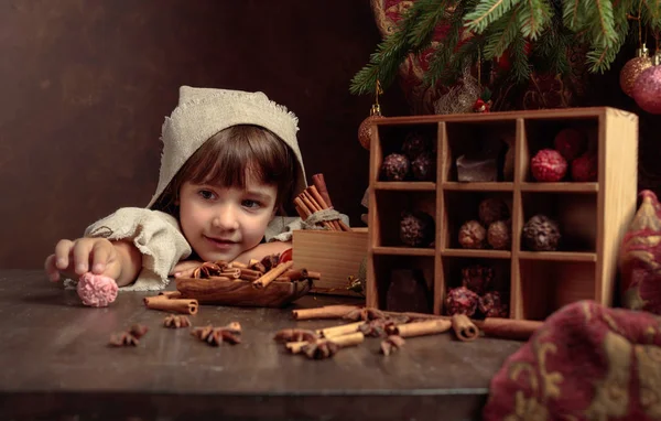 Маленькая девочка в винтажном льняном платье рядом со столом со сладостями — стоковое фото