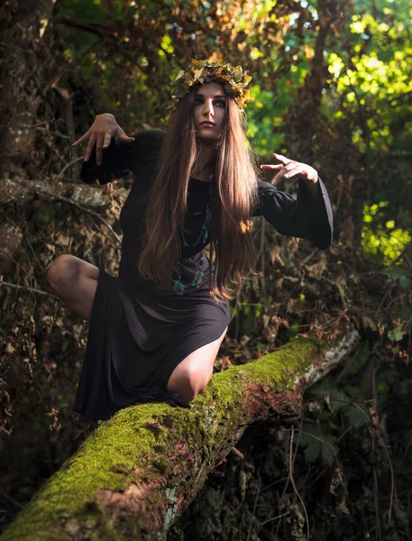 Mujer joven con el pelo largo en traje de bruja en el bosque . — Foto de Stock