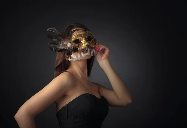 Junge attraktive Frau in schwarzem Kleid mit goldenem Karneval — Stockfoto