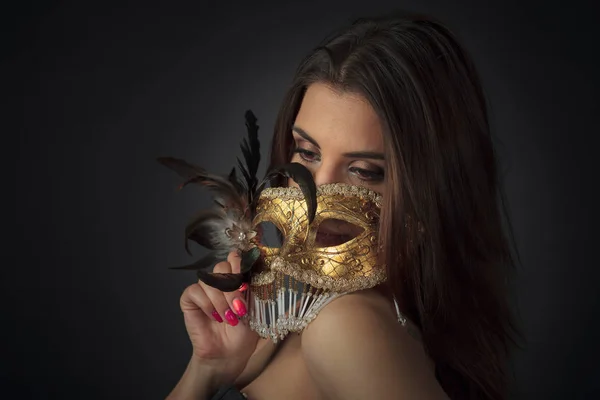 Young attractive woman in a black dress with golden carnival mas — Stock Photo, Image