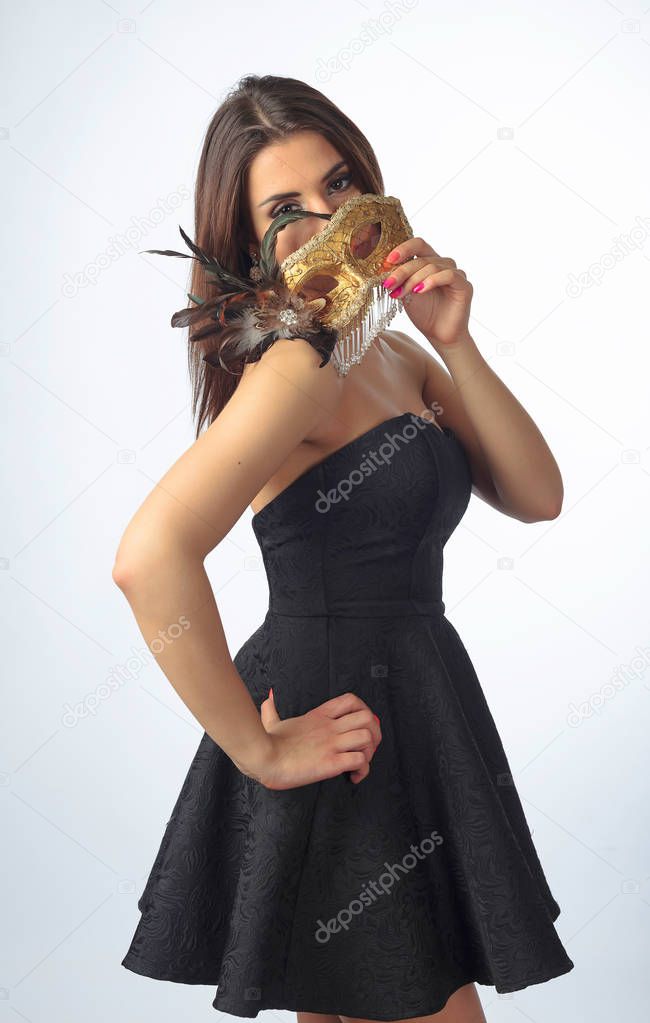 Young attractive woman  with golden carnival mask on white backg