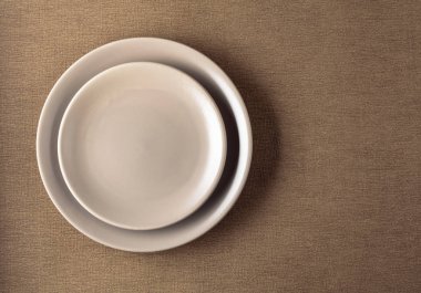 Bej masa örtüsü üzerinde boş seramik yuvarlak bej plaka.