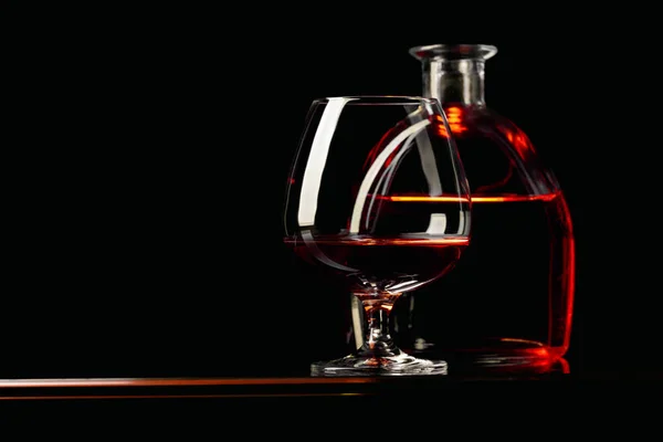 Bicchiere e bottiglia di brandy su sfondo nero . — Foto Stock