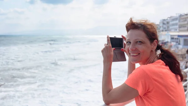 Приваблива зріла мандрівник жінка використовує мобільний телефон зробити фотографію — стокове фото