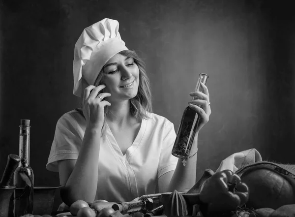 Mladá krásná dívka v uniformě kuchařky s malými lahvemi s olem — Stock fotografie