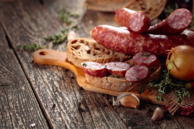 Eski ahşap bir masada ekmek ve baharat ile kuru-tedavi sosis.