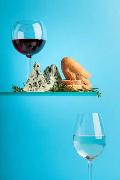 Queijo azul com pão, vinho e alecrim sobre fundo azul . — Fotografia de Stock