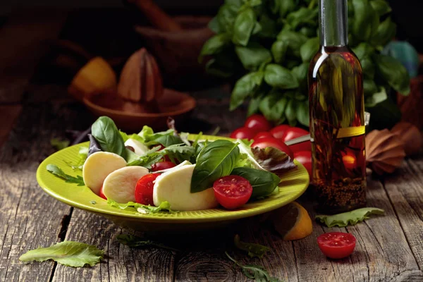 Ensalada verde con mozzarella, tomate y albahaca en plato verde sobre —  Fotos de Stock