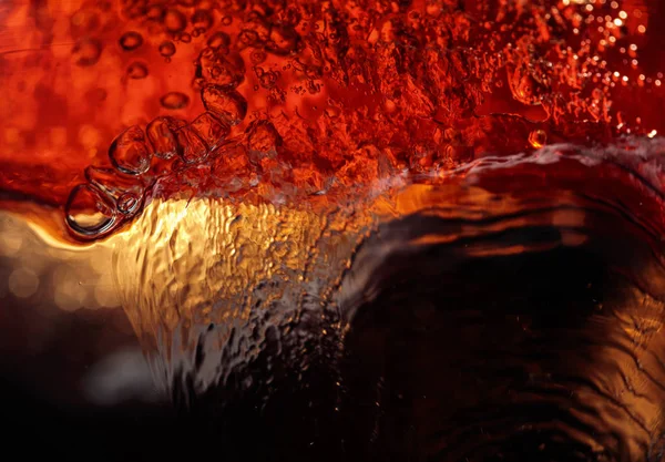 Alcoholic drink on a dark background, abstract splashing. — Stock Photo, Image