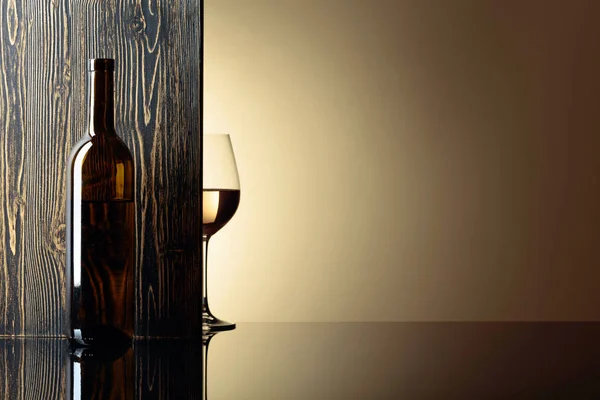 Fles en glas witte wijn op een zwarte tafel. — Stockfoto