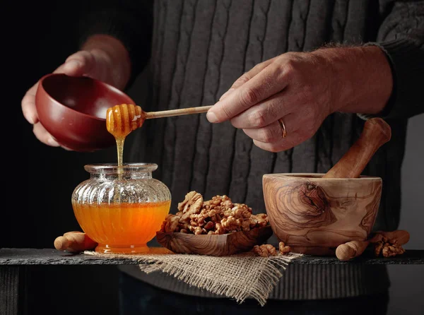 Man i en tröja förbereder en frukost med valnötter och honung. — Stockfoto