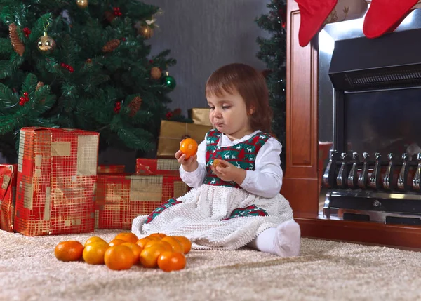 Маленькая девочка с мандаринами в комнате с рождественскими украшениями — стоковое фото