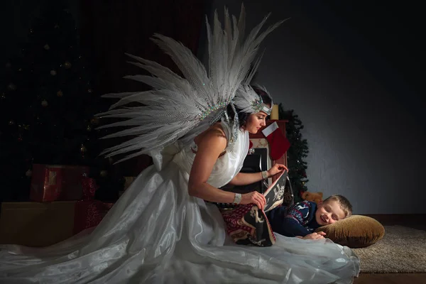 Женщина в белом костюме ангела с крыльями и спящим мальчиком возле Че — стоковое фото