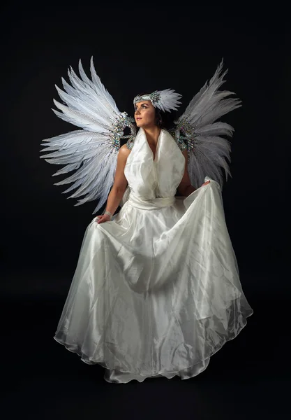 Frau im weißen Engelskostüm mit Flügeln auf schwarzem Hintergrund. — Stockfoto