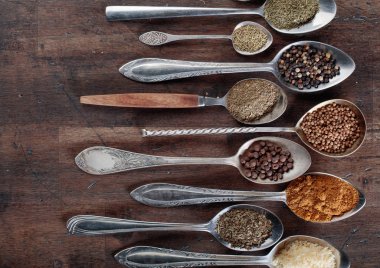 Ahşap arka plan üzerinde kaşık içinde farklı baharatlar. 