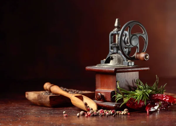 Alte Pfeffermühle mit Kochutensilien, verschiedenen Paprikaschoten und Rosema — Stockfoto