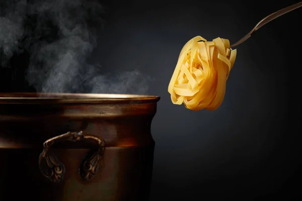 Tagliatelle all'uovo crude fatte in casa e vecchia padella in ottone con acqua calda . — Foto Stock