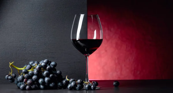 Red wine grapes on a black table and glass of red wine. Royalty Free Stock Photos