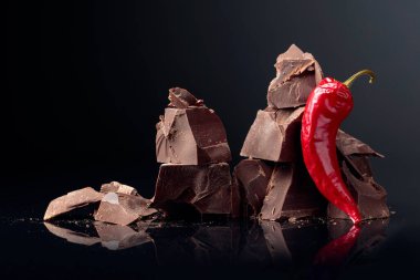 Koyu bir arka plan üzerinde kırmızı biber ile koyu çikolata parçaları. 