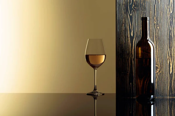 Flasche und Glas Weißwein auf schwarzem Tisch. — Stockfoto