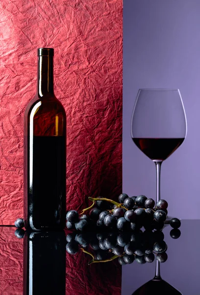 Bottle and glass of red wine on a black table. — Stock Photo, Image