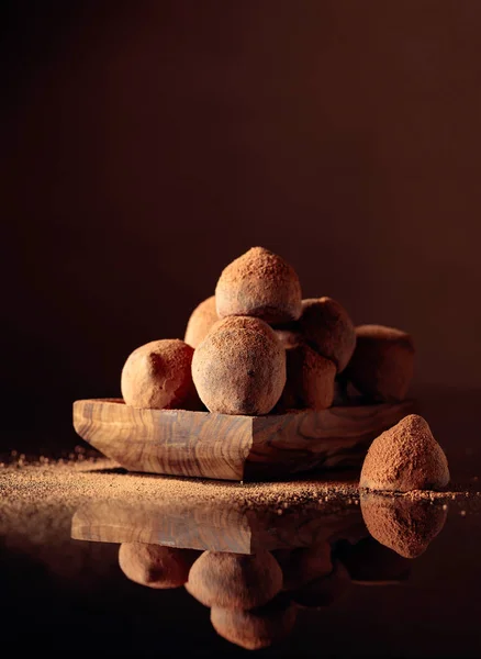 Trufas de chocolate en un pequeño plato de madera espolvoreado con cacao pow — Foto de Stock