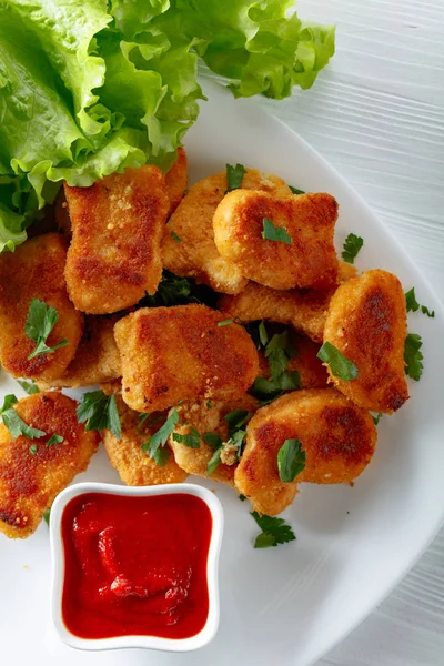 Fried chicken nuggets with ketchup sprinkled with chopped parsle