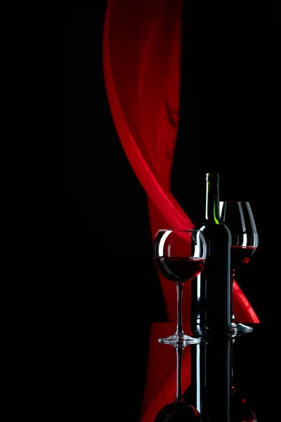 Wine glasses and bottle of red wine on a black reflective backgr — Stock Photo, Image