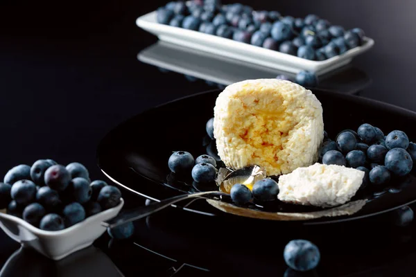 Cottage cheese with honey and blueberry on a black plate. — Stock Photo, Image