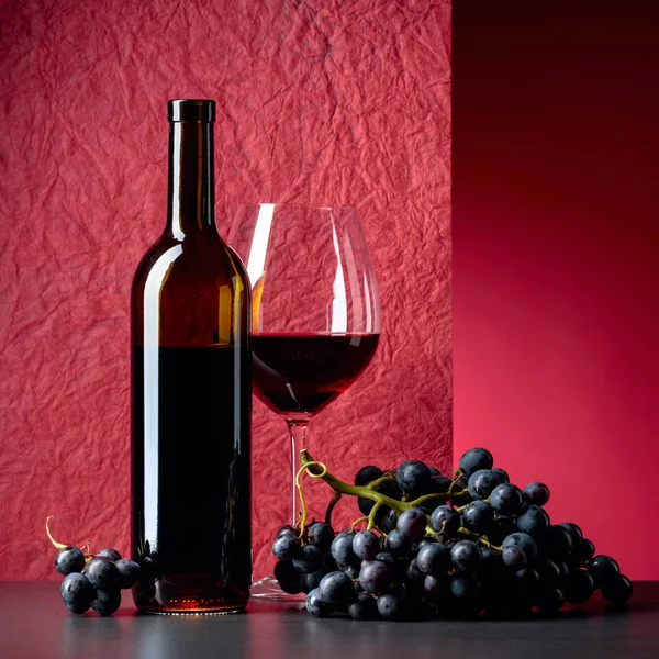 Bottle and glass of red wine on a red background. — Stock Photo, Image