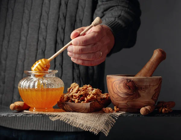 Man i en tröja förbereder en frukost med valnötter och honung. — Stockfoto