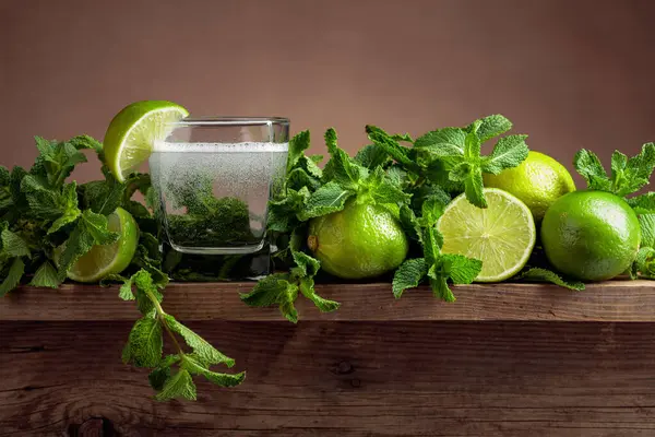 Carbonated drink or cocktail with limes and mint on a old wooden table.