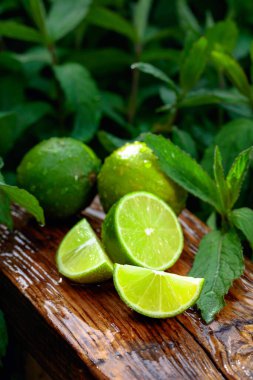 Bahçede ve limonlarda nane yetişiyor. Eski ahşap arka planda kireç dilimleri ve nane yaprakları.