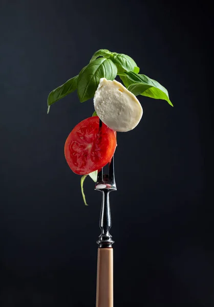 黒を基調としたトマトとグリーンバジルのモッツァレラ — ストック写真