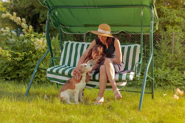 年轻的祖母和孙女在夏天的花园里爱抚一只狗 — 图库照片