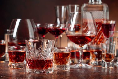 Set of strong alcoholic beverages in glasses on a brown background. In the presence of liquor, whiskey, vodka, rum, brandy, tequila.  clipart