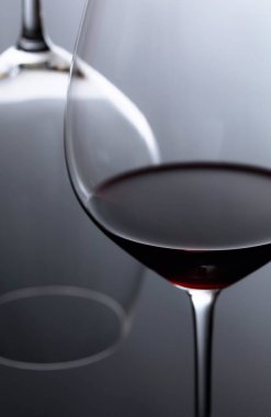 Siyah yansıtıcı arka planda bir kadeh kırmızı şarap. Seçici fokus.
