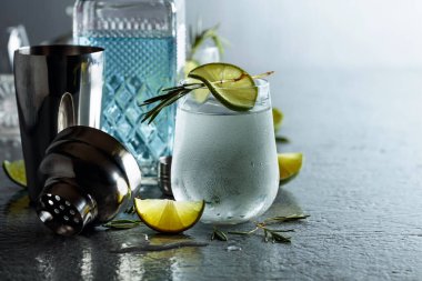 Biberiyeli cin toniği ve buzlu bardakta limon. Gri metal arka planda kokteyl. Boşluğu kopyala.