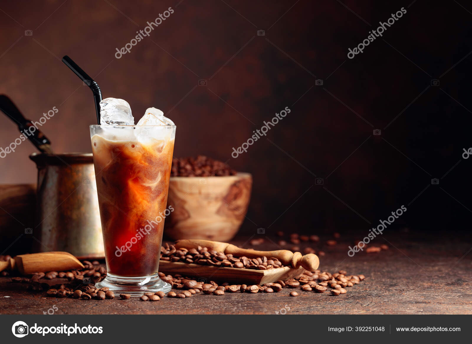 Ice coffee in a glass with cream poured over and coffee beans
