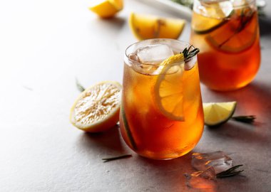 Limonlu, limonlu ve biberiye dallarıyla süslenmiş geleneksel buzlu çay. Limon dilimli dondurulmuş bardaklar. Boşluğu kopyala.