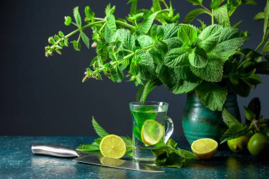 Limonlu nane çayı ve koyu arkaplanda bir demet taze nane. Boşluğu kopyala.