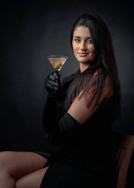 Yeşil zeytinli sek martini içen çekici bir kız. Güzel esmer, siyah bardaklı, soğuk kokteylli.