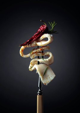 Çatalda tuzlanmış baharatlı domuz yağı. Koyu arkaplanda kırmızı biber ve biberiyeli domuz yağı..