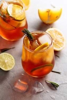 Limonlu, limonlu ve biberiye dallarıyla süslenmiş geleneksel buzlu çay. Turunçgil dilimli donmuş bardaklar..