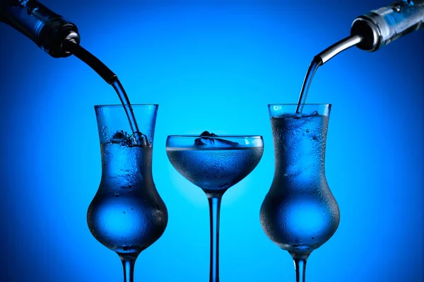 Vodka Hälls Från Flaskor Glas Med Blå Bakgrund — Stockfoto