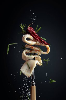 Kırmızı biberli, tuzlu ve biberiyeli bir dilim baharatlı domuz yağı. Koyu arkaplanda baharatlı domuz yağı.