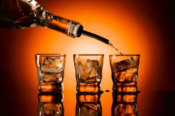Silny Alkohol Wlewa Się Szklanek Lodem Czarne Odblaskowe Tło Pomarańczowe — Zdjęcie stockowe