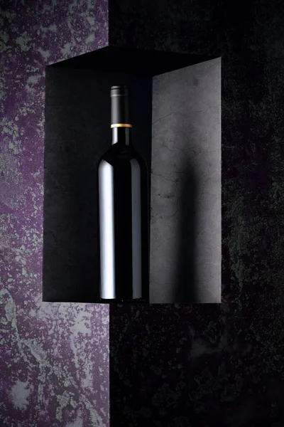 Unopened bottle of red wine on a dark background. Copy space for your text.
