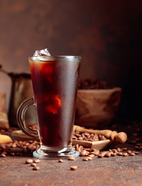 Ledová Káva Přehrazeném Skle Kávová Zrna Starém Hnědém Stole Kuchyňským — Stock fotografie